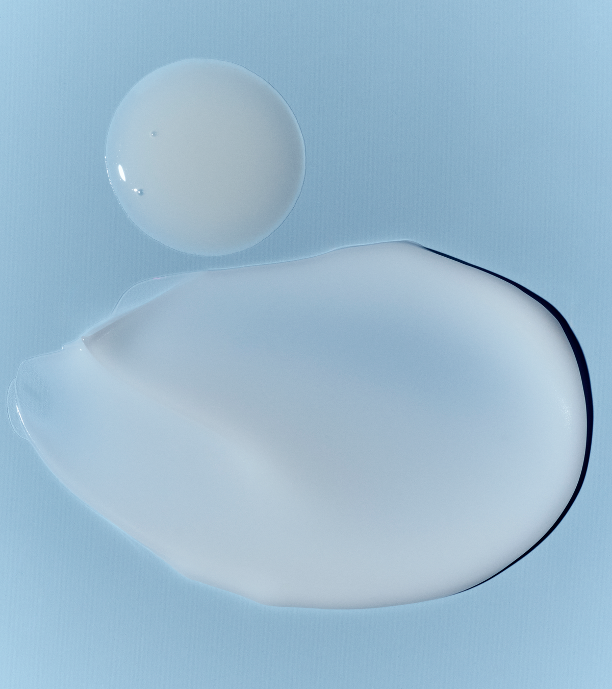 dieux Dieux-the-repair-firm-duo-moisturizer-circular-drop-and-translucent-smear-on-light-blue-background.